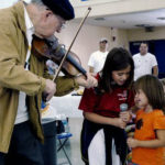 senior playing violin with young girl singer