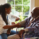 senior balck man recieves care from black caregiver