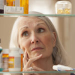 Senior woman looking through medicine cabinet