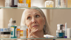 Senior woman looking through medicine cabinet