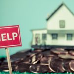 large pile of pennies in formt of a house with HELP sign