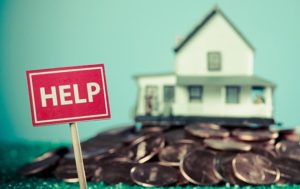 large pile of pennies in formt of a house with HELP sign