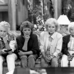 All the stars of "The Golden Girls" TV show sitting on a couch, leaning in to watch TV
