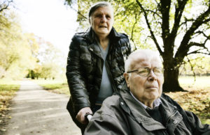 older woman pushing senior man in wheelchair