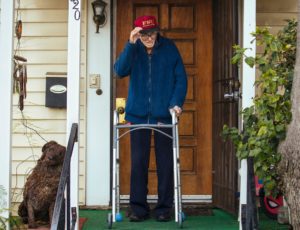 elderly man with walker in front of home